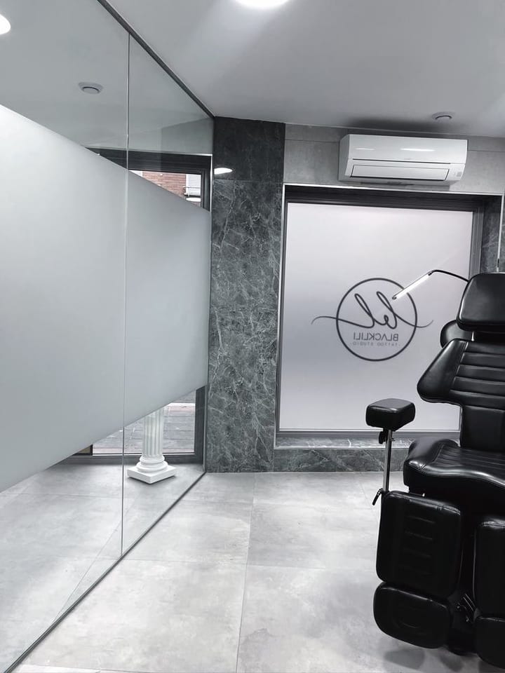 Sala de tatuaje del estudio BlackLili Tattoos con sillón y logo en cristal