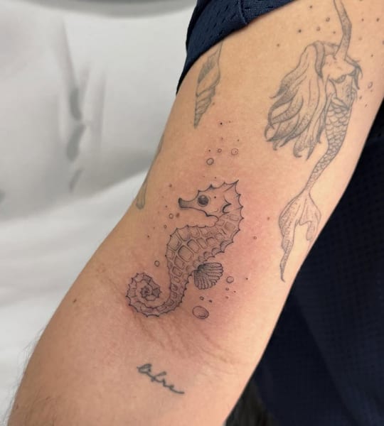 Tatuaje de caballito de mar en línea fina, brazo — Madrid