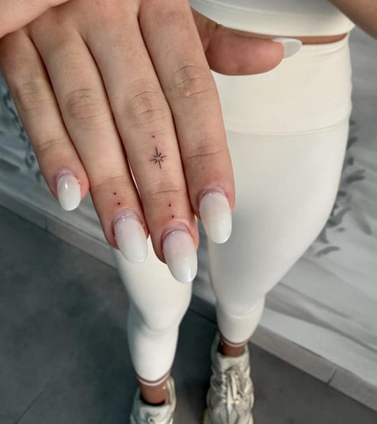 Micro tatuaje minimalista de estrella y puntos en línea fina, dedo