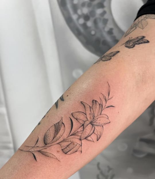 Tatuaje botánico de lirio en línea fina, antebrazo — Madrid